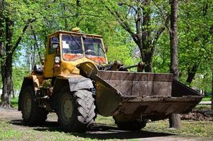 el equipo de mejora de la ciudad quita las hojas caídas en el parque con una excavadora y un camión. trabajo estacional regular en la mejora de los lugares públicos para la recreación foto