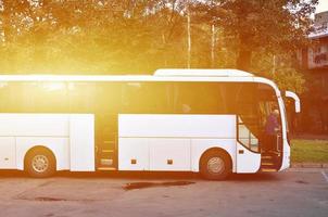 autobús turístico blanco para excursiones. el autobús está estacionado en un estacionamiento cerca del parque foto