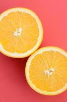 Top view of a several orange fruit slices on bright background in red color. A saturated citrus texture image photo