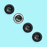 A few camera lenses with a closed aperture lie on texture background of fashion pastel blue color paper photo