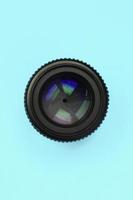 Camera lens with a closed aperture lie on texture background of fashion pastel blue color paper photo