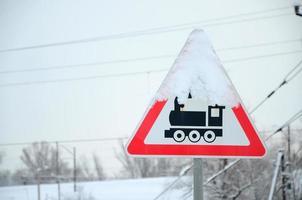 Railway crossing without barrier. A road sign depicting an old black locomotive, located in a red triangle photo