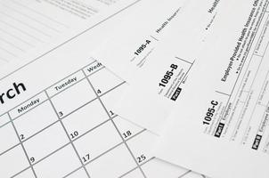 IRS Form 1095-A 1095-B and 1095-C blank lies on empty calendar page photo