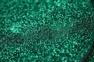 A huge amount of green decorative sequins. Background texture with shiny, small elements that reflect light in a random order. Glitter texture photo