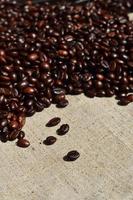 Texture of a gray canvas made of old and coarse burlap with coffee beans on it photo