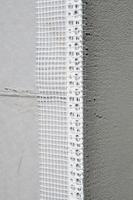 The texture of the wall, covered with gray polystyrene foam plates, which are coated with a reinforcing mixture with a plastic reinforcing profile corner. Stage of wall insulation photo