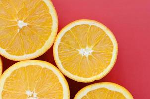 Top view of a several orange fruit slices on bright background in red color. A saturated citrus texture image photo