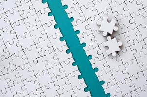The blue path is laid on the platform of a white folded jigsaw puzzle. The missing elements of the puzzle are stacked nearby. Texture image with space for text photo