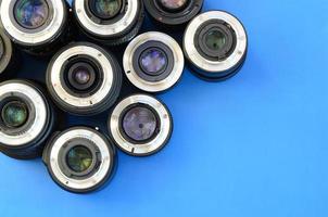 Several photographic lenses lie on a bright blue background. Space for text photo