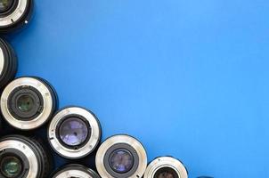 Several photographic lenses lie on a bright blue background. Space for text photo