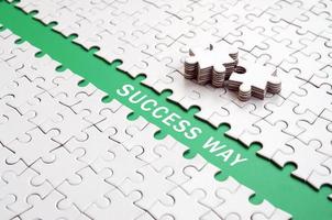 Success way. The green path is laid on the platform of a white folded jigsaw puzzle. The missing elements of the puzzle are stacked nearby photo