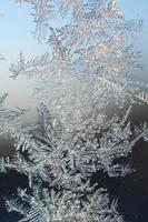 Snowflakes frost rime macro on window glass pane photo