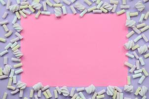 Colorful marshmallow laid out on violet and pink paper background. pastel creative textured framework. minimal photo