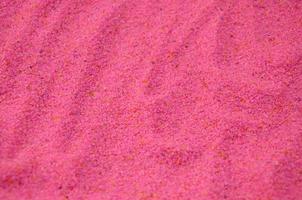 Texture of a colored granular sand close up. Pink grains photo