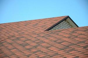 The roof is covered with bituminous shingles of brown color. Quality Roofing photo