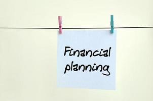 Financial Planning. Note is written on a white sticker that hangs with a clothespin on a rope on a background of beige wall photo