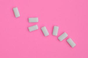 unos cuantos chicles se encuentran en el fondo de textura del papel de color rosa pastel de moda en un concepto mínimo foto