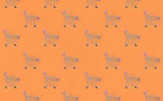 Shopping addiction, shopping lover or shopaholic concept. Many small empty shopping carts perform a pattern on a pastel colored paper background. Flat lay composition, top view photo