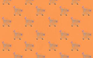 Shopping addiction, shopping lover or shopaholic concept. Many small empty shopping carts perform a pattern on a pastel colored paper background. Flat lay composition, top view photo