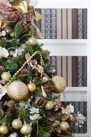 A beautiful decorated Christmas tree on the background of a bookshelf with many books of different colors. Christmas background image of the library photo