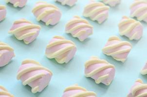 Colorful marshmallow laid out on blue paper background. pastel creative textured pattern. Perspective macro shot photo