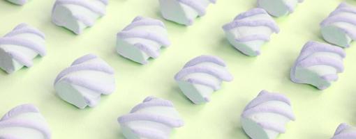 Colorful marshmallow laid out on lime paper background. pastel creative textured pattern photo