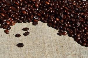 Texture of a gray canvas made of old and coarse burlap with coffee beans on it photo