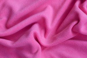 The blanket of furry pink fleece fabric. A background of light pink soft plush fleece material with a lot of relief folds photo