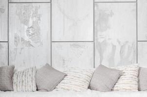 Many pillows lie on the couch, which is covered with a large plush veil against the background of a marble wall photo