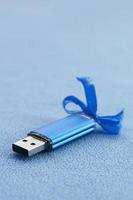 la tarjeta de memoria flash usb azul brillante con un lazo azul se encuentra sobre una manta de tela de vellón azul claro suave y peluda. diseño clásico de regalo femenino para una tarjeta de memoria foto