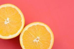 Top view of a several orange fruit slices on bright background in red color. A saturated citrus texture image photo