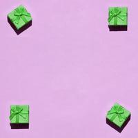 Many small green gift boxes on texture background of fashion trendy pastel pink color paper photo