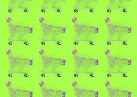 Shopping addiction, shopping lover or shopaholic concept. Many small empty shopping carts perform a pattern on a pastel colored paper background. Flat lay composition, top view photo
