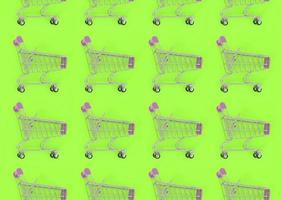 Shopping addiction, shopping lover or shopaholic concept. Many small empty shopping carts perform a pattern on a pastel colored paper background. Flat lay composition, top view photo