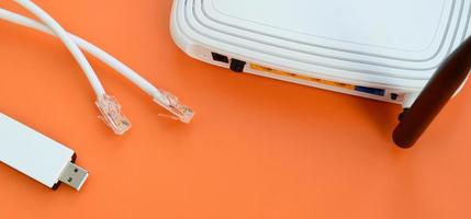 Internet router, portable USB wi-fi adapter and internet cable plugs lie on a bright orange background. Items required for internet connection photo