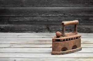 The heavy and rusty old coal iron lies on a wooden surface photo