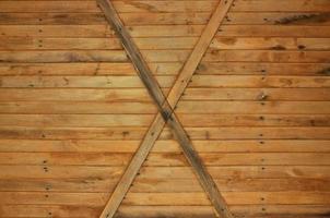 textura de una antigua valla de tablones horizontales de madera naranja con tableros cruzados foto