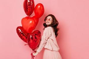 foto de estudio de la sensual chica jengibre con globos en forma de corazón rojo. foto interior de una mujer hermosa