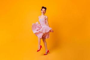 Full length view of wonderful woman in polka-dot dress. Studio shot of ginger girl dancing on yello photo