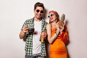Charming girl in sunglasses and stylish orange outfit and her boyfriend posing on white background photo
