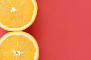 Top view of a several orange fruit slices on bright background in red color. A saturated citrus texture image photo