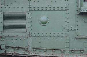 Texture of tank side wall, made of metal and reinforced with a multitude of bolts and rivets photo