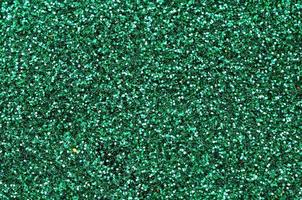 una gran cantidad de lentejuelas decorativas verdes. textura de fondo con elementos pequeños y brillantes que reflejan la luz en un orden aleatorio. textura brillo foto