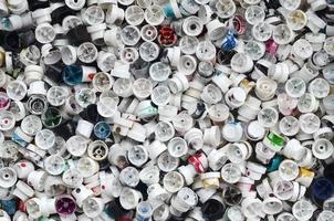 A large number of caps from cans of aerosol paint for graffiti. Smeared with colored paint nozzles lie in a huge pile photo