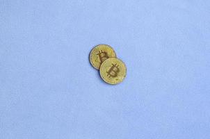 Two golden bitcoins lies on a blanket made of soft and fluffy light blue fleece fabric. Physical visualization of virtual crypto currency photo