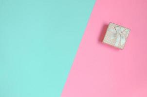 Small pink gift box lie on texture background of fashion pastel blue and pink colors paper in minimal concept photo