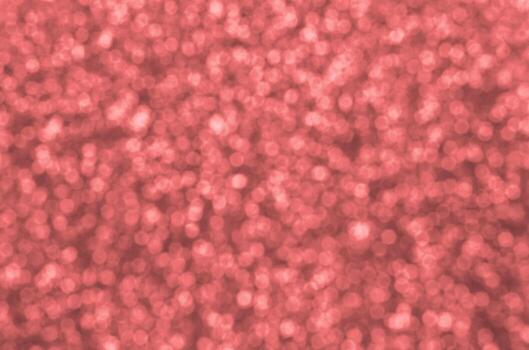 Blurred coral red decorative sequins. Background image with shiny bokeh lights from small elements photo