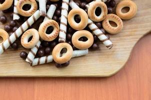 túbulos crujientes, bolas de chocolate y bagels yacen sobre una superficie de madera. mezcla de varios dulces foto