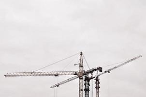 Abstract Industrial background with construction tower cranes over clear blue sky. Construction site. Building under construction concept. Retro tone photo