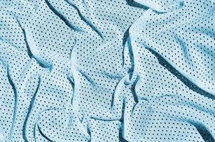 Sport clothing fabric texture background. Top view of light blue polyester nylon cloth textile surface. Colored basketball shirt with free space for text photo